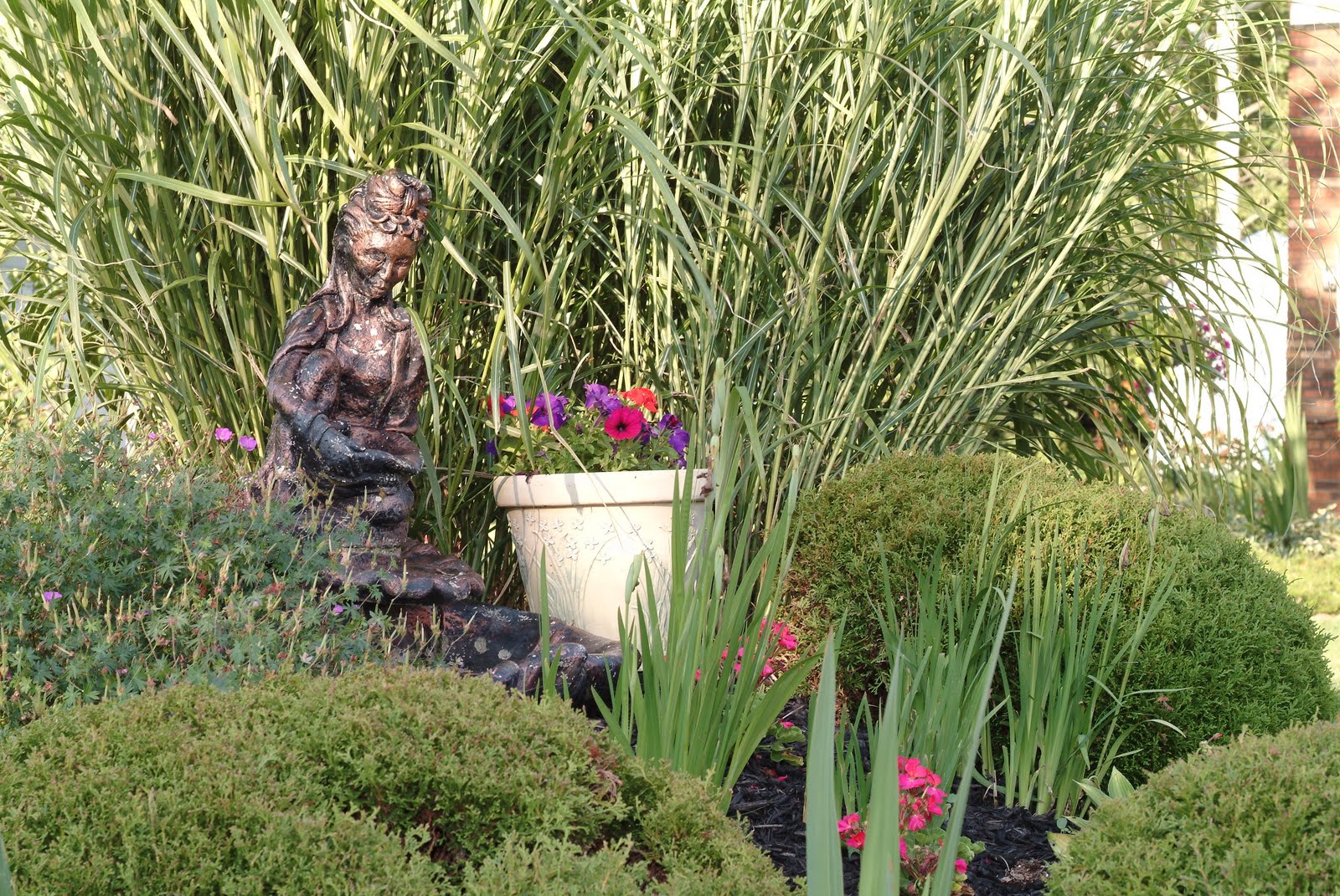 A decorative statue watches over spring blossoms in this garden